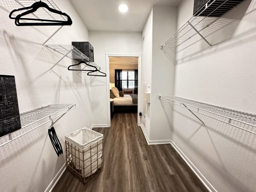 a walk in closet with shelves and a basket on the floor at Grand Villas Apartments, Katy