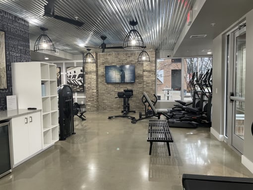 a gym with weights machines and a tv on a brick wall
