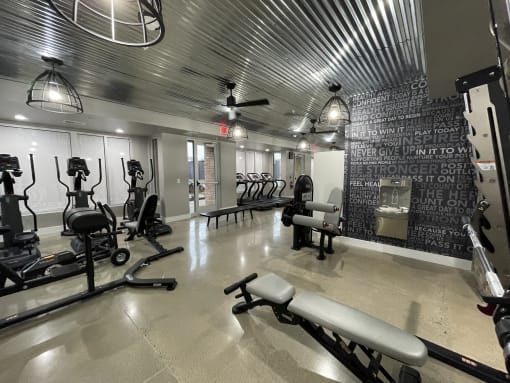 a workout room with weights and chairs and a chalkboard wall in a gym