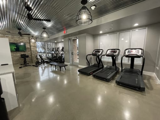 a gym with treadmills and other exercise equipment in a building with glass doors