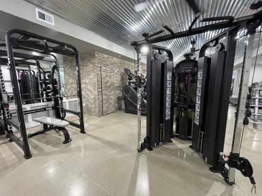a gym with weights machines and other equipment in a building with galvanized ceilings