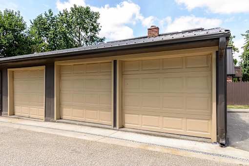 Three car garage with beige overhead doors at London House Apartments, Kansas
