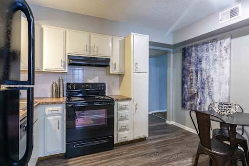 Modern kitchen with white cabinets and black appliances at London House Apartments, Kansas, 66215