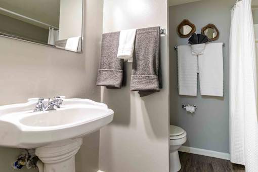 Guest bathroom with pedestal sink and towel display at London House Apartments, Lenexa, Kansas