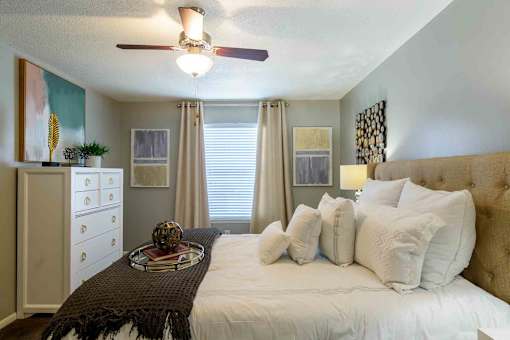 Bedroom with upholstered headboard and white bedding at London House Apartments, Lenexa