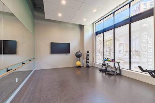 A spacious room with a television, exercise equipment, and large windows.