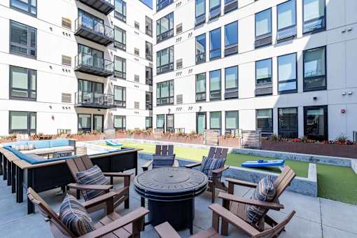 A patio with a table and chairs is surrounded by apartment buildings.