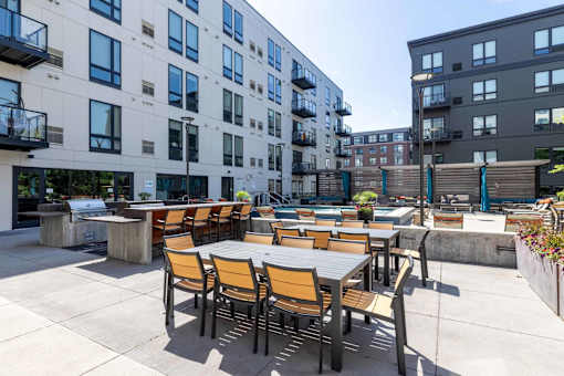 A patio with tables and chairs is surrounded by apartment buildings.