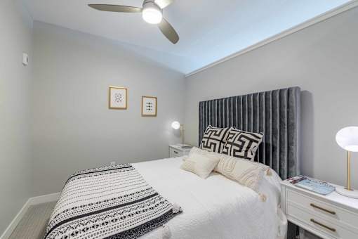 A bedroom with a bed, nightstand, and two wall art pieces.