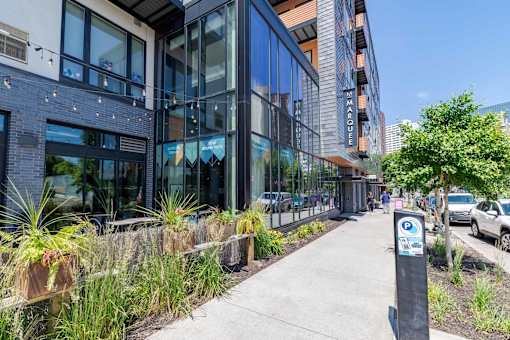 A modern building with a glass facade and a parking sign on the sidewalk.