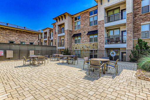 a patio with tables and chairs outside of an apartment building at Discovery at Craig Ranch, McKinney