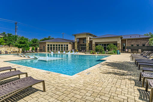 a swimming pool with chairs and a building in the background at Discovery at Craig Ranch, McKinney, TX, 75070