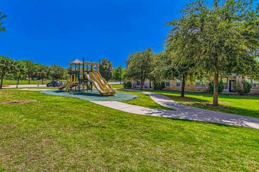 a playground in a park with green grass and trees at Discovery at Craig Ranch, McKinney, Texas