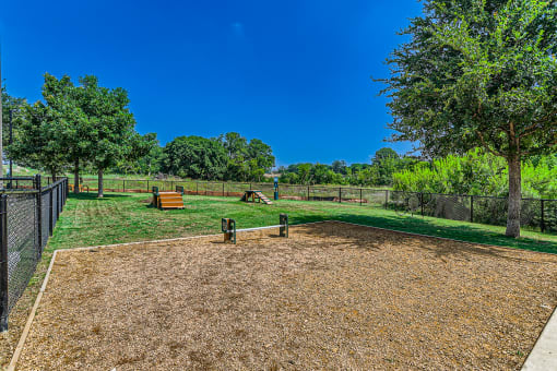 a fenced in dog park with trees and a bench at Discovery at Craig Ranch, Texas, 75070