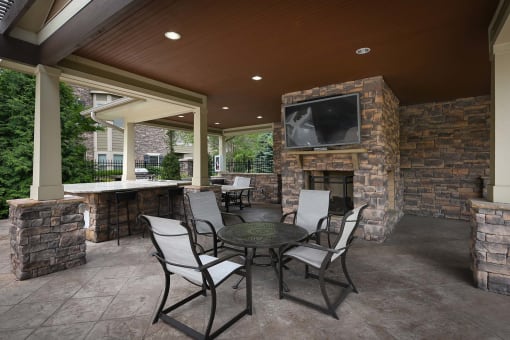a covered patio with a table and chairs and a fireplace at Sovereign at Overland Park, Kansas
