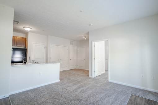 A spacious living room with a kitchen area to the left and a doorway leading to another room. at Overland Park, Pickerington, Ohio
