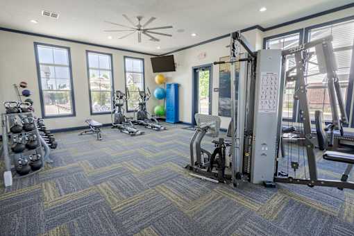 A gym with a variety of equipment including a weight rack, treadmill, and exercise balls. at Overland Park, Pickerington, 43147