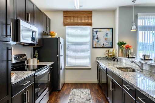A kitchen with black cabinets and granite countertops. at Penn Circle, Carmel