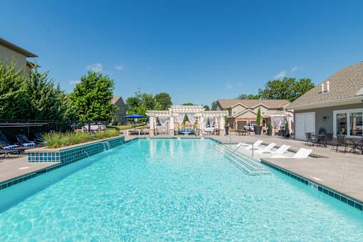 A large swimming pool with a blue tiled edge and a white fence around it.