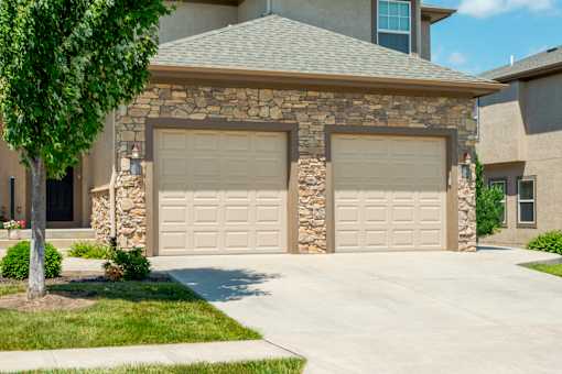 A house with a stone pillar and two garage doors.