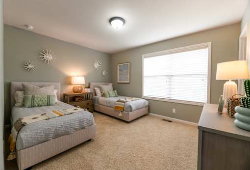 A bedroom with two beds and a nightstand with a lamp.