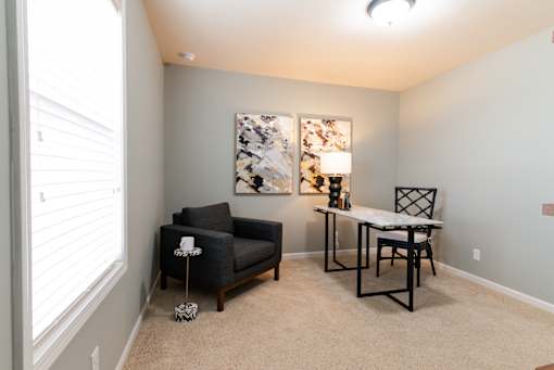 A living room with a black chair and a table with a lamp on it.