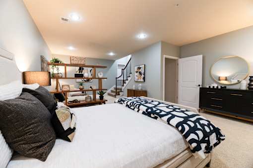 A bedroom with a large bed and a dresser with a mirror.