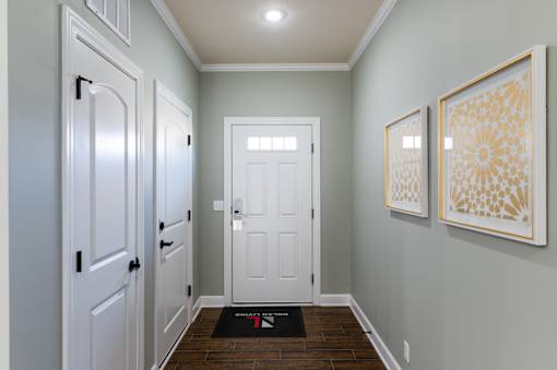 A hallway with a white door and two framed pictures on the wall.