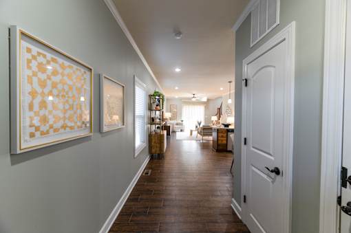 A hallway with a white door and two framed pictures on the wall.