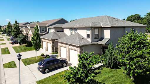A grey car is parked in front of a house.