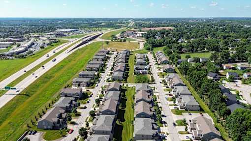A suburban neighborhood with rows of houses and a highway in the background.