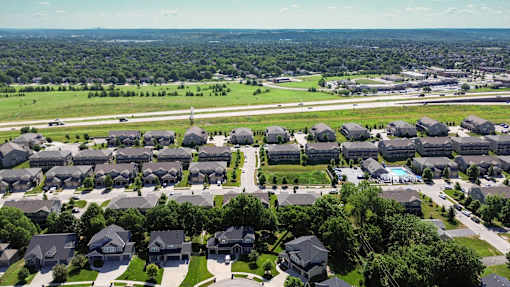 A bird's eye view of a residential area with houses and a swimming pool.