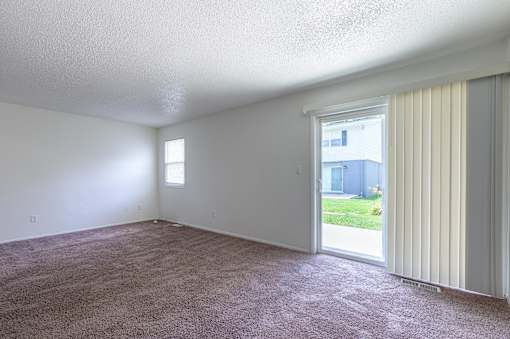 A room with a carpeted floor and a sliding glass door at Spring Creek Townhomes Apartments, Springfield, IL 62702