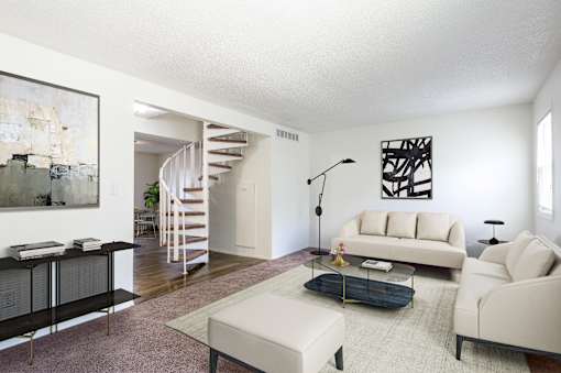 A living room with a white couch, a black coffee table, and a spiral staircase at Spring Creek Townhomes Apartments, Springfield 62702