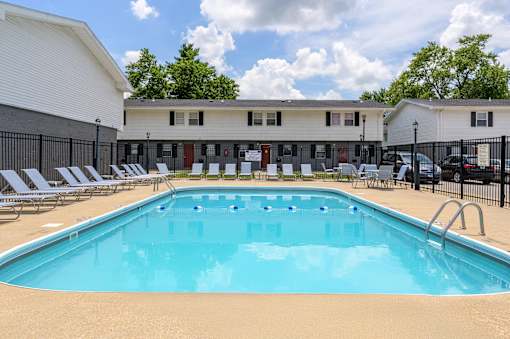 A large swimming pool in front of a building with lounge chairs around it at Spring Creek Townhomes Apartments, Springfield, IL
