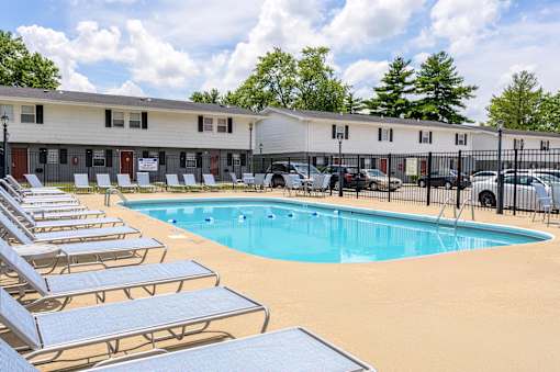 A pool surrounded by sun loungers and a building in the background at Spring Creek Townhomes Apartments, Illinois