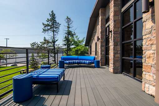 A wooden deck with blue seating and a stone pillar.