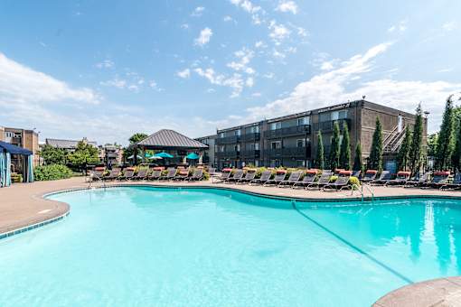 A large swimming pool with lounge chairs and a building in the background.