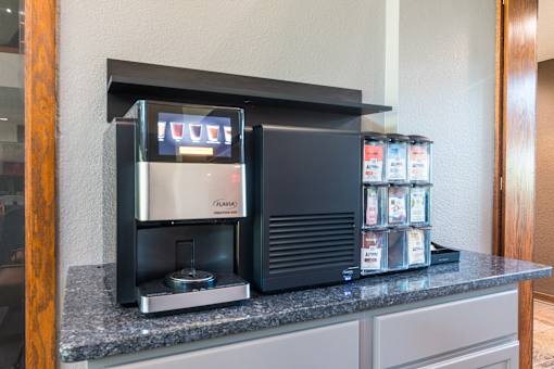 A coffee machine is on a counter with a display showing the word "coffee".
