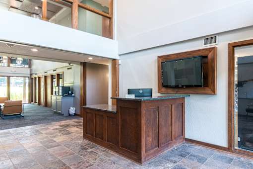 A reception area with a wooden desk and a television on the wall.