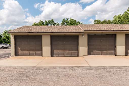 A building with three garage doors is in front of a tree.