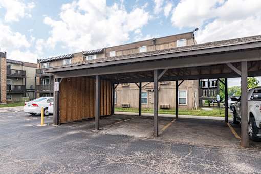 A parking lot with a wooden structure and cars parked.