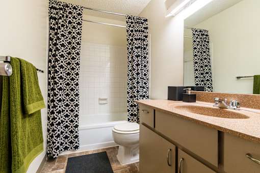 A bathroom with a toilet, sink, and shower curtain.