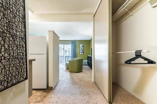 A hallway with a white fridge and a green chair.