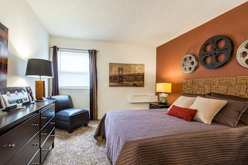 A bedroom with a bed, dresser, and window.