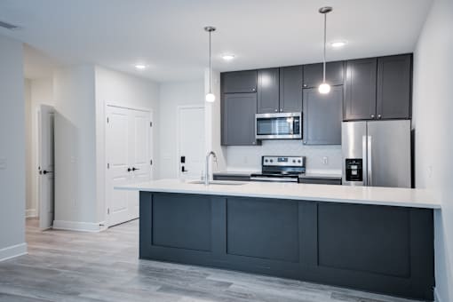 A modern kitchen with a white countertop and dark grey cabinets. at The MK, Indiana
