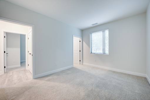 A room with white walls and carpeted floor with two doors. at The MK, Indiana