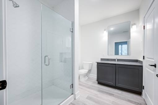 A bathroom with a walk-in shower and a vanity with a mirror. at The MK, Indiana, 46220