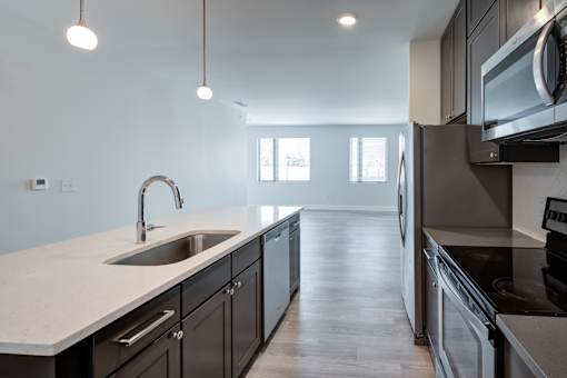 A modern kitchen with dark wood cabinets and stainless steel appliances. at The MK, Indianapolis
