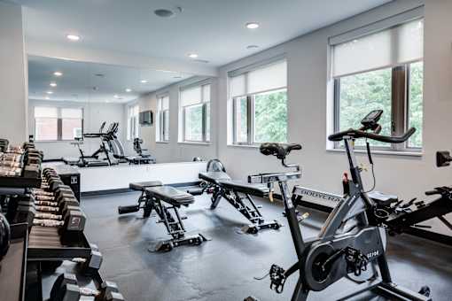 A gym with a row of treadmills and stationary bikes. at The MK, Indiana, 46220